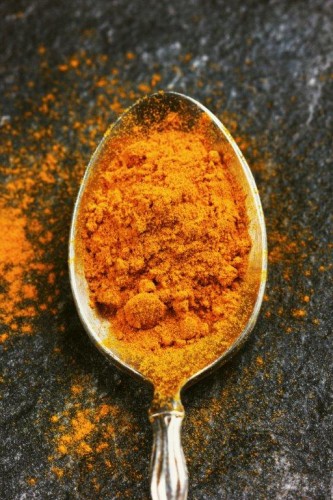 tumeric powder in a silver spoon